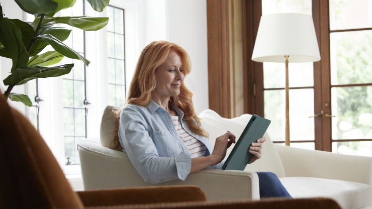 Woman sitting on a couch looking a tablet